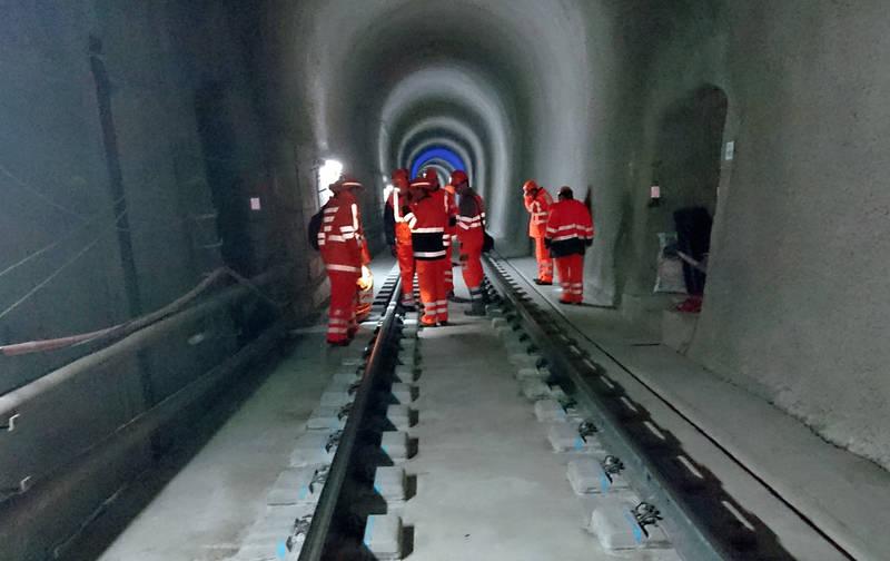 Oelberg tunnel after the reconstruction: A Bunch of workers in orange protection wear stand inside a tunnel.